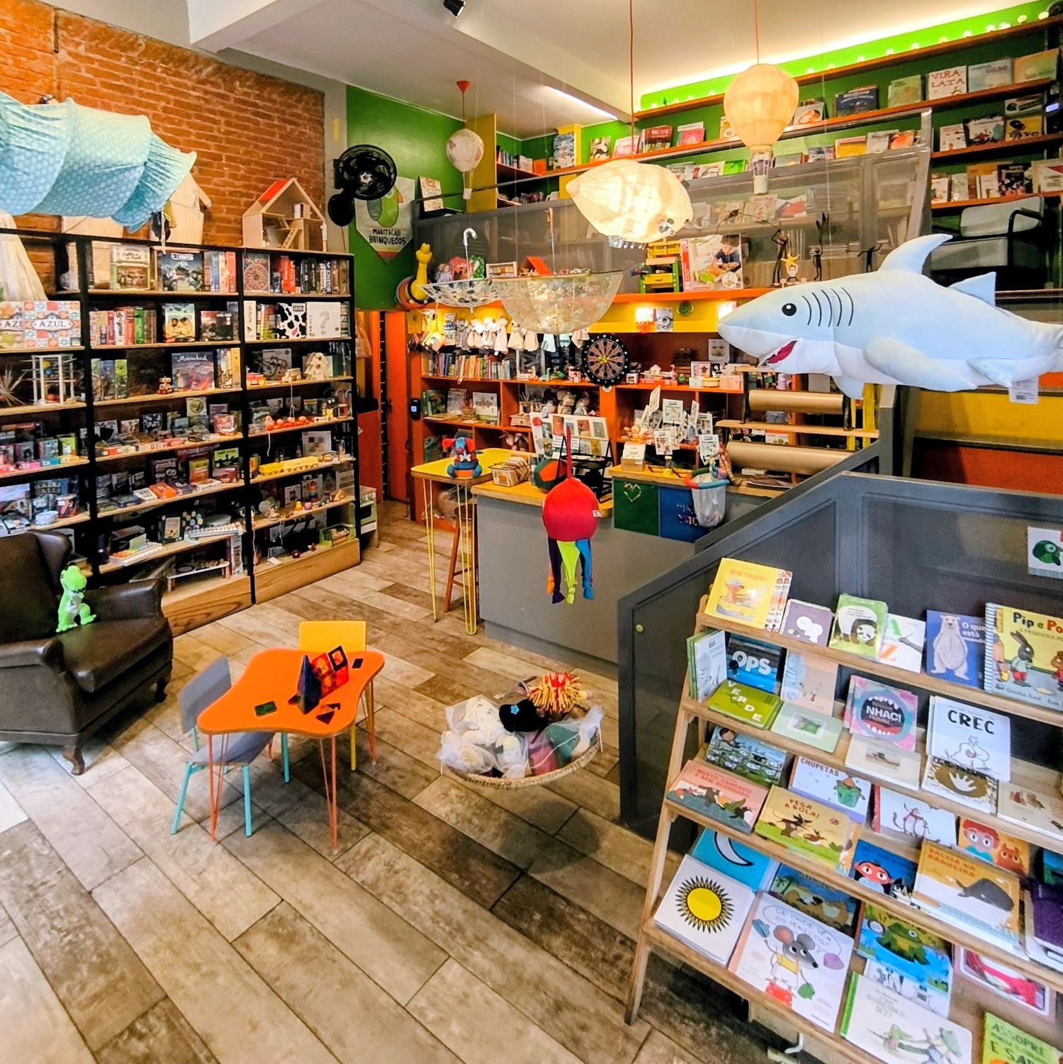 Interior da Maritaca, com prateleiras de livros e jogos, poltrona de leitura, mesinha para as crianças e balões decorativos